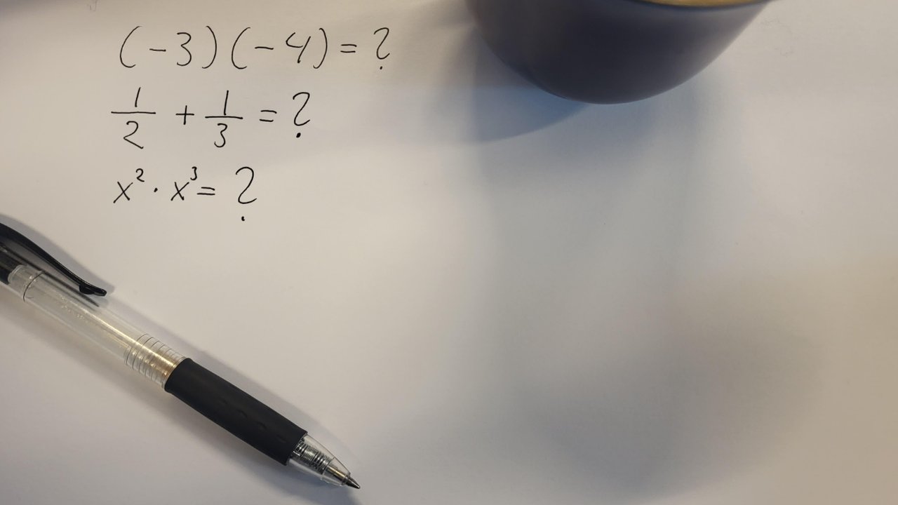 Handskrivna mattefrågor på ett papper bredvid en penna och en kaffekopp: (−3)(−4) = ?, 1/2 + 1/3 = ? och x² · x³ = ?